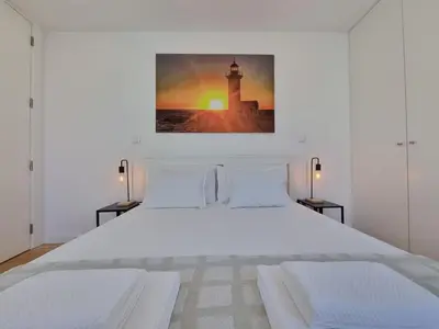 a bedroom with a white bed with a picture on the wall at Ponte & Morro Apartment in Vila Nova de Gaia