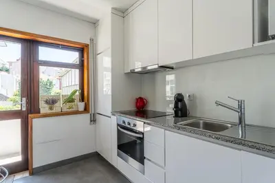 a kitchen with white cabinets and a sink and a window at GuestReady - Home Comforts in Porto in Porto