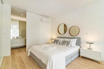 a white bedroom with a large bed with two mirrors at Bright Studio in Porto in Porto