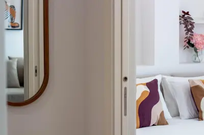 a mirror on a wall next to a bed with pillows at Stylish & Cozy 1BR with AC by LovelyStay in Porto