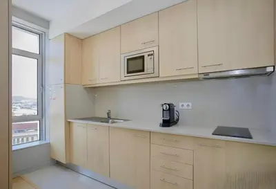 a kitchen with white cabinets and a microwave and a window at Oporto Blue Dragão - Modern Uptown Studio With Free Parking in Porto