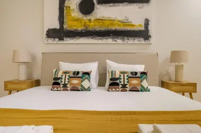 a bedroom with a white bed with pillows and a painting at Art Deco 14 Luxury Apartment Downtown Metro AC in Porto