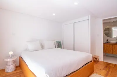 a white bedroom with a large bed and a mirror at Chic Campanhã Home w Free Parking by LovelyStay in Porto