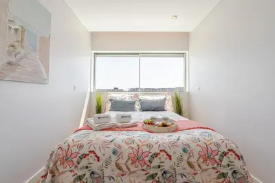 a bedroom with a large bed with a large window at Stylish Home with Balcony & Garage by HostWise in Porto