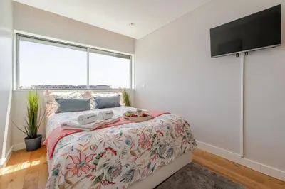 a bedroom with a bed and a flat screen tv at Stylish Home with Balcony & Garage by HostWise in Porto