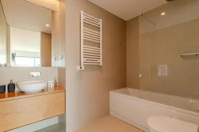a bathroom with a sink and a tub and a toilet at Stylish Home with Balcony & Garage by HostWise in Porto