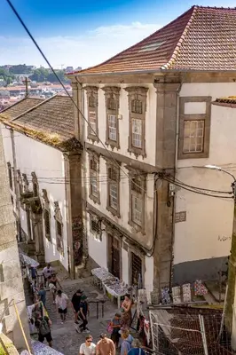a group of people walking down a street next to buildings at Porto Haven - Under the Luís I Bridge in Porto