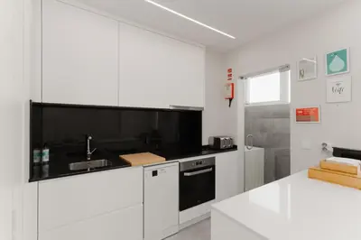 a white kitchen with a sink and a stove at Fernão de Magalhães in Porto