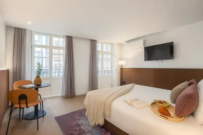 a hotel room with a bed and a flat screen tv at Aspasios Baixa Apartments in Porto
