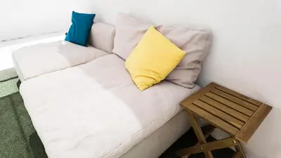 a white couch with two pillows and a wooden stool at Bonfim Residence in Porto