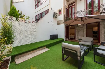 an outdoor patio with green grass and an umbrella at Central Porto Hideaway with Sunny Terrace by Lisbeyond in Porto