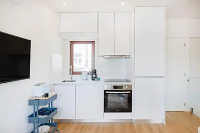 a white kitchen with white cabinets and a tv at Clérigos Loft | 111 Collection in Porto