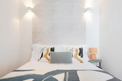 a white bedroom with a bed and a living room at Clérigos Loft | 111 Collection in Porto