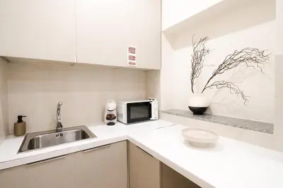 a white kitchen with a sink and a microwave at Bleu Alma Apartment in Porto