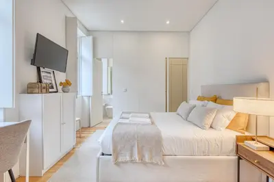 a white bedroom with a bed and a flat screen tv at OPORTO GUEST Downtown Escape in Porto