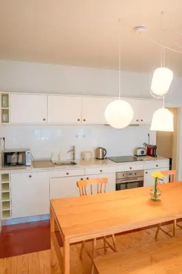 a kitchen with white cabinets and a wooden table at Porto Breeze in Porto