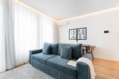 a blue couch in a living room with white curtains at GuestReady - The perfect urban retreat in Porto