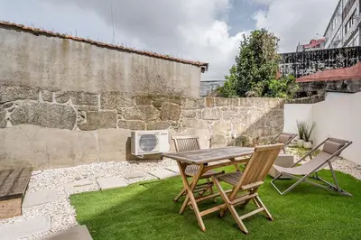 a patio with a table and chairs on the grass at GuestReady - The perfect urban retreat in Porto