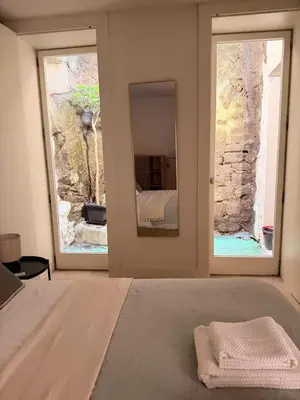 a bedroom with a bed with a mirror and two windows at Guindais River View I in Porto