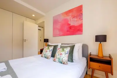 a bedroom with a white bed and a painting on the wall at Magnolia 5 Luxury with AC Metro Downtown Porto in Porto
