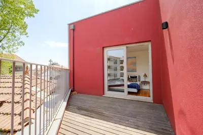 a balcony of a red building with a sliding glass door at Magnolia 5 Luxury with AC Metro Downtown Porto in Porto