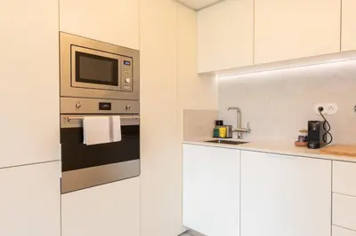 a kitchen with white cabinets and a microwave at Chic 1-BR Flat in Award-Winning Building in Porto