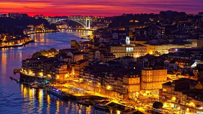 a city lit up at night with a river and buildings at porto true confession in Porto