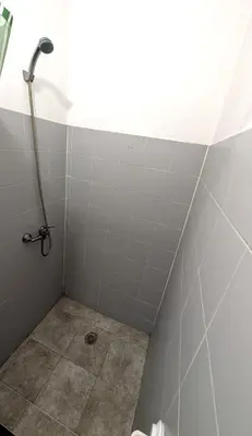 a bathroom with a shower and a tiled wall at Riko Guesthouse in Porto