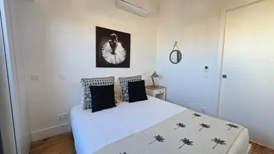 a bedroom with a white bed with black pillows at Fontainhas Sunny Rooftop with balcony in Porto