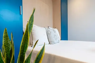 a white bed with two pillows and a plant at Stylish Flat with Workspace & Garage by HostWise in Porto