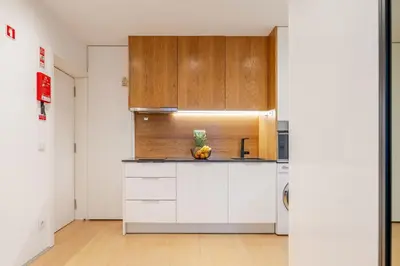 a kitchen with white cabinets and a wooden wall at Stylish Flat with Workspace & Garage by HostWise in Porto