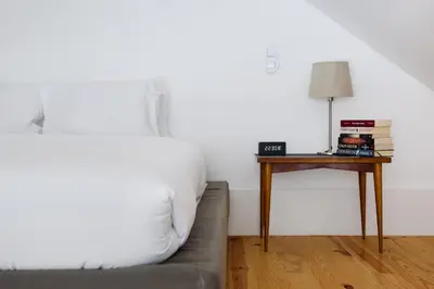 a bedroom with a bed and a table with a lamp at Cool Alegria Loft Mezzanine Retreat in Porto