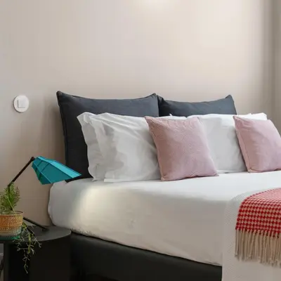 a bed with pink and white pillows on it at Baumhaus Serviced Living - Art & Design Apartments in Porto