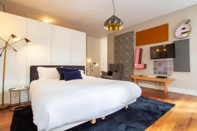 a bedroom with a large white bed and a desk at Cardosas Bright Studio by LovelyStay in Porto