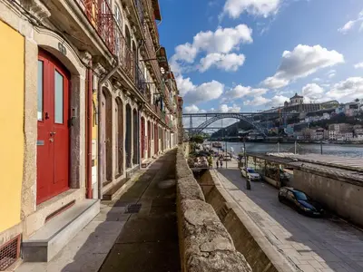 a building with a red door next to a river at Apartment with Balcony for 4 Guests in Porto