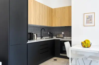 a kitchen with black cabinets and a white table at Bright Flat | Romantic Escape by HostWise in Porto