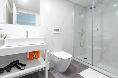 a white bathroom with a shower and a toilet at NorteSoul OldTown - 2 Bedroom 2 Bathroom Apartment! in Porto