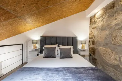 a bedroom with a large bed and a stone wall at Lapa 4 House in Porto
