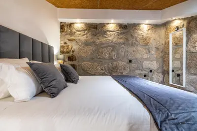 a bedroom with a white bed with a stone wall at Lapa 4 House in Porto