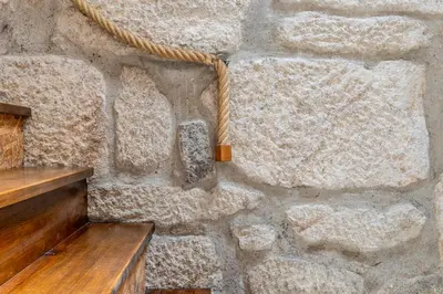 a stone wall with a wooden bench and a rope at Lapa 4 House in Porto