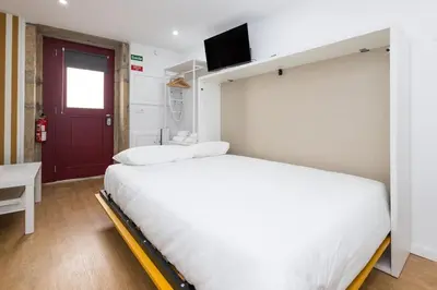 a bedroom with a white bed and a red door at Cozy Studios Porto Sao Lazaro in Porto
