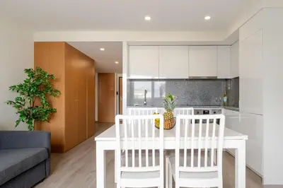 a kitchen and living room with a white table and chairs at Modern & Sleek Flat | Terrace & Garage by HostWise in Porto