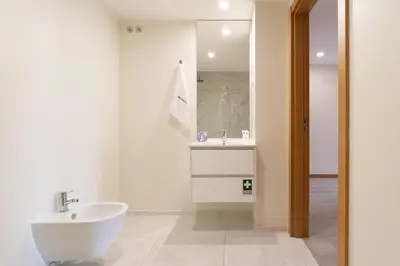 a white bathroom with a sink and a mirror at Modern & Sleek Flat | Terrace & Garage by HostWise in Porto