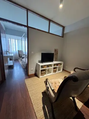 a living room with a couch and a chair and a television at Casa da Música Apartment in Porto