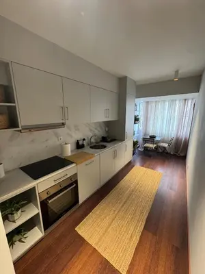 a kitchen with white cabinets and a wooden floor at Casa da Música Apartment in Porto