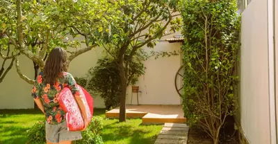 a woman standing in a garden holding a surfboard at Porto Surf Lodge in Porto