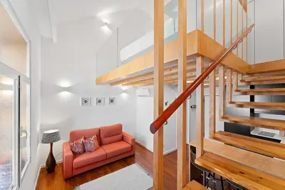 a living room with a staircase and a red couch at GuestReady - Lovely nook with mezzanine in Porto