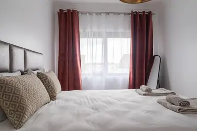 a bedroom with a bed and a window with red curtains at Purely Porto in Porto