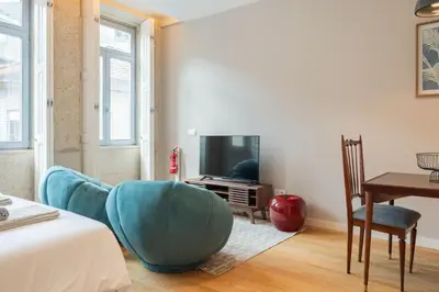 a bedroom with a bed and a tv and a chair at Oliveirinhas Boutique Flats in Porto