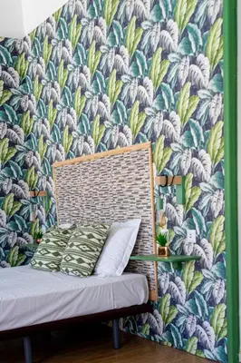 a bed against a wall with a floral wallpaper at St Catarina Flats in Porto